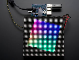 Top view of Adafruit RGB Matrix HAT + RTC assembled onto a Pi and matrix LED panel. The LED panel displays an off-set square rainbow gradient.