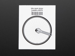 Circular sticker of a bicycle wheel in black and grey with a wrench turning the central nut, over a white background. Mounted on white paper with barcode. 