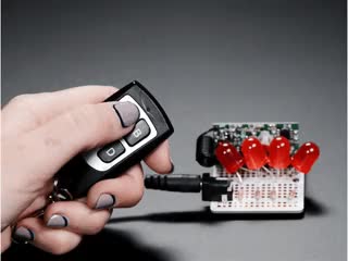 Hand pressing buttons on Keyfob 4-Button RF Remote Control and controlling LEDs on a project