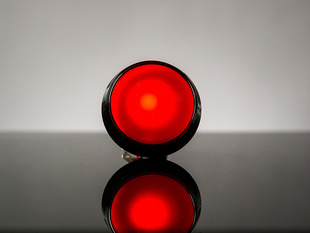 head-on shot of illuminated large red arcade button with LED.