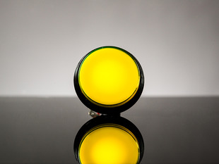 head-on shot of illuminated large yellow arcade button with LED.