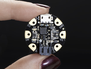 Purple poslished fingers holding a Adafruit GEMMA v2 - Miniature wearable electronic platform. 