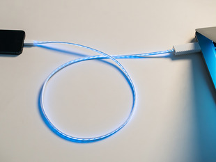 Lit up USB cable to lightening between computer and iPhone.