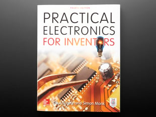 Front cover of "Practical Electronics for Inventors, Fourth Edition". Covert art is a detailed close-up of a chip being placed on a circuit board.