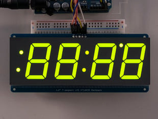 Huge green 7-segment clock display soldered to backpack with all segments lit