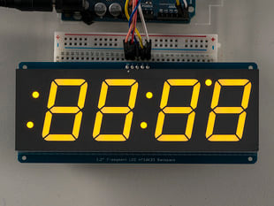 Huge yellow 7-segment clock display soldered to backpack with all segments lit