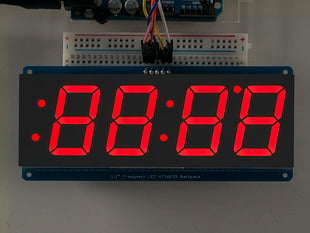 Huge red 7-segment clock display soldered to backpack with all segments lit