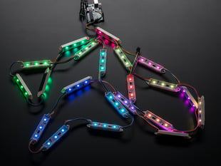 Cluster of many lit up LED pixel bars on wire strand, rainbow colored