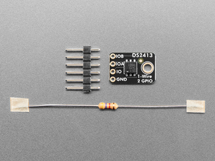 Overhead shot of small, black, rectangular GPIO controller breakout board next to a 6-pin header and one resistor.