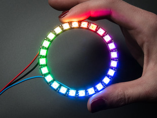 Hand holding NeoPixel Ring with 24 x 5050 RGB LED, lit up rainbow