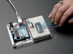Capacitive Touch Sensor Breakout on breadboard with hand touching many attached wires