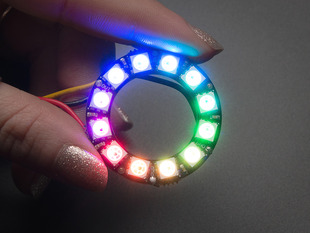 Hand holding NeoPixel Ring with 12  x 5050 RGB LED, lit up rainbow