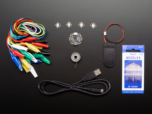 Kit contents shot with circular microcontroller with copper pads, needles, coin cell battery holder, sewable LEDs, micro USB to USB-A cable, alligator clips, and conductive sewing thread.
