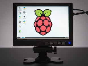Front view of assembled and powered on HDMI 4 Pi - 7" Display. The monitor displays a desktop background with a raspberry logo.
