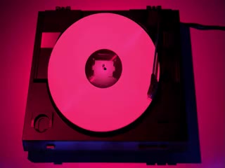 Pink-hued video of a pink vinyl record playing on a record player.