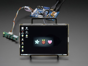 Angled shot of a HDMI 4 Pi: 7" Display & Audio. Display. The monitor displays a desktop background with a adafruit logo + raspberry logo = heart. 