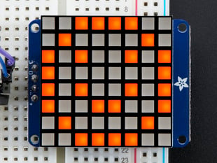 Close-up of Soldered and assembled Small 1.2" 8x8 Ultra Bright Square Amber LED Matrix + Backpack on a breadboard powered by an Arduino Uno. The LED Matrix displays an orange smiley.