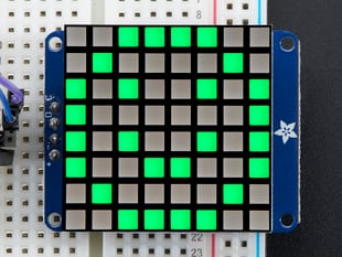 Close-up of soldered and assembled Small 1.2" 8x8 Ultra Bright Square Green LED Matrix + Backpack on a breadboard powered by an Arduino Uno. The LED Matrix displays a green smiley.