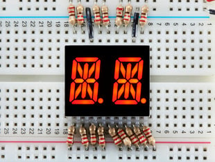 Red Dual Alphanumeric Display module wired to breadboard, all segments lit