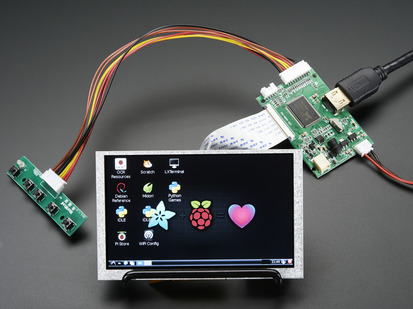 Angled shot of an assembled HDMI 4 Pi: 5" Display (no Touch) w/Mini Driver. The HDMI screen displays a desktop image including the Adafruit logo, the Raspberry Pi logo, and a pink heart.