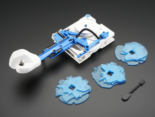 Angled shot of assembled Auto Writing Machine kit along with three blue plates and small hand tool.