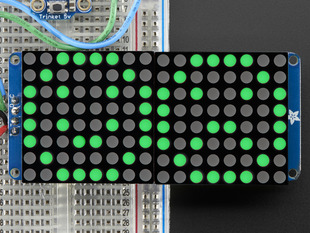 Close-up of Soldered and assembled 16x8 1.2" LED Matrix + Backpack - Ultra Bright Round Green LEDs on a breadboard. The LED Matrices display a smiling emoji and a frowning emoji.