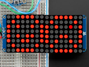 Close-up of Soldered and assembled 16x8 1.2" LED Matrix + Backpack - Ultra Bright Round Red LEDs on a breadboard. The LED Matrices display a smiling emoji and a frowning emoji.
