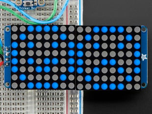 Close-up of Soldered and assembled 16x8 1.2" LED Matrix + Backpack - Ultra Bright Round Blue LEDs on a breadboard. The LED Matrices display a smiling emoji and a frowning emoji.