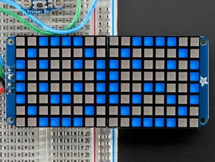 Close-up of Soldered and assembled 16x8 1.2" LED Matrix + Backpack - Ultra Bright Square Blue LEDs on a breadboard. The LED Matrices display a smiling emoji and a frowning emoji.
