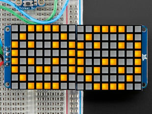 Close-up of Soldered and assembled 16x8 1.2" LED Matrix + Backpack - Ultra Bright Square Yellow LEDs on a breadboard. The LED Matrices display a smiling emoji and a frowning emoji.