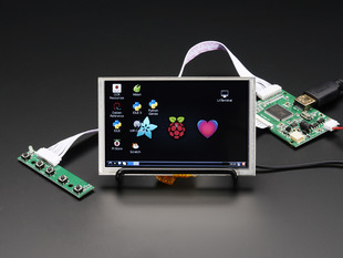Angled shot of an assembled HDMI 4 Pi: 5" Display w/Touch and Mini Driver. The HDMI screen displays a desktop image including the Adafruit logo, the Raspberry Pi logo, and a pink heart.