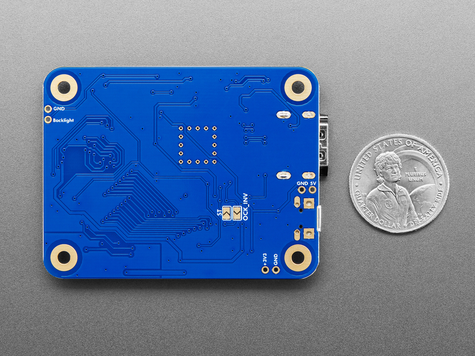 Back of blue, rectangular PCB next to US quarter for scale.