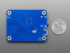 Back of blue, rectangular PCB next to US quarter for scale.
