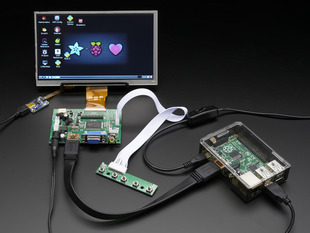 Front shot of a HDMI 4 Pi: 7" Display connected to a Raspberry Pi. The monitor displays a desktop background with a adafruit logo, raspberry logo, and a heart. 
