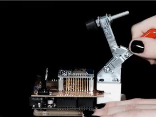 Video of a white hand manipulating a toggle clamp to press a PCB onto a prototype tester with pogo pins.