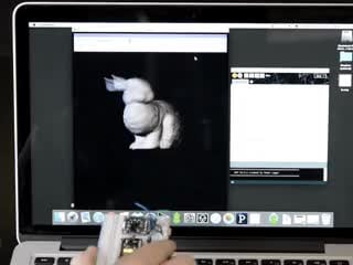 Video of a white hand moving a white hand moving a white breadboard around with a Adafruit 9-DOF Absolute Orientation IMU Fusion Breakout connect to it. Display on macbook shos a 3d image of a rabit stimulating the movements of the white hand. 