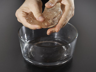 White hand holding a blob of melted Low Temperature Thermoplastic.