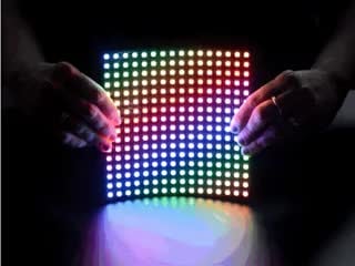 Video of two white hands holding a rainbow pulsing Flexible 16x16 NeoPixel RGB LED Matrix.
