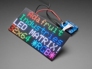Adafruit RGB Matrix Shield for Arduino connected to a LED Matrix that reads "Adafruit Industries LED MATIX! 32x64 *RGB*"