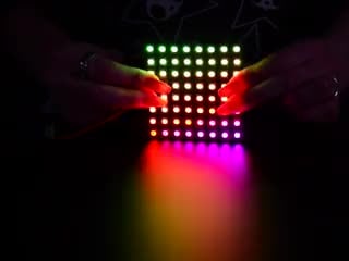Two hands flexing a rainbow pulsing Flexible Adafruit DotStar Matrix 8x8 - 64 RGB LED Pixels.