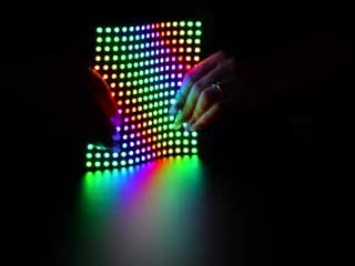 Two hands flexing a rainbow pulsing Flexible Adafruit DotStar Matrix 16x16 - 256 RGB LED Pixels.