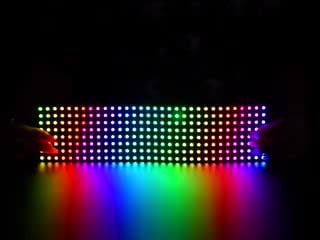Two hands flexing a rainbow pulsing Flexible Adafruit DotStar Matrix 8x32 - 256 RGB LED Pixels.