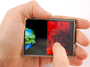 Hand holding TFT screen with finger swiping between two photos