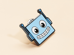 Angled shot of blue enamel pin resembling a friendly robot.