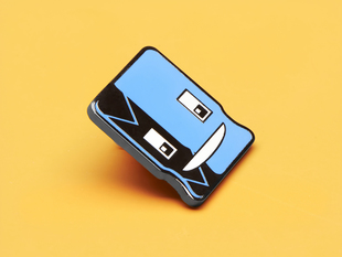 Angled shot of blue with a black strip enamel pin resembling a smiling face capacitor 
