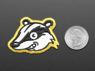 Embroidered badge in the shape of a grinning black and white Privacy Badger logo, trimmed in yellow.