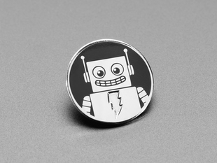 Angled shot of a black and silver enamel pin with an image resembling an friendly robot. 