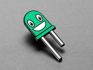 Angled shot of an enamel pin resembling a happy green LED.