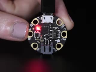 Pink polished fingers holding a Adafruit GEMMA M0 - Miniature wearable electronic platform. 