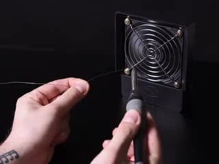 Person using fan to vent away solder smoke